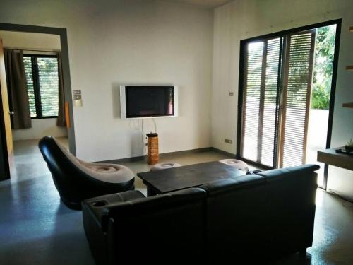 - un salon avec un canapé, une table et une télévision dans l'établissement Baba pim villa, à Chiang Mai