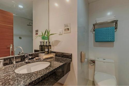 a bathroom with a sink and a toilet and a mirror at Huangshan Tiandu International Hotel in Huangshan