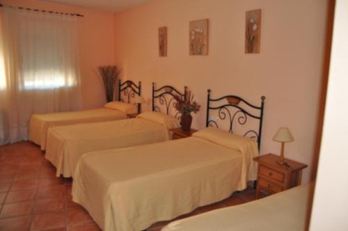 a hotel room with three beds with white sheets at Hostal Paulino in Trujillo
