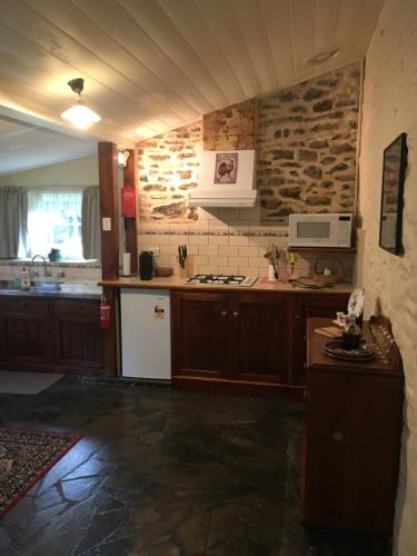 a kitchen with wooden cabinets and a stone wall at Gasworks B&B Cottages in Strathalbyn