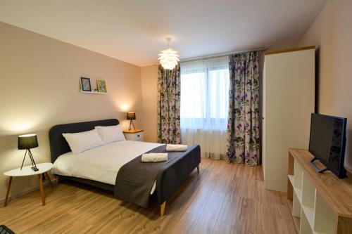 a bedroom with a large bed and a television at Mandarin Premium Apartments in Târgu-Mureş