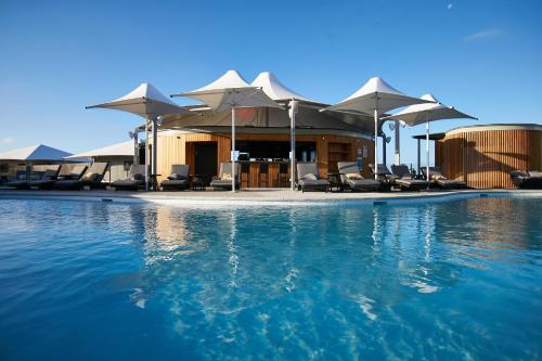 a swimming pool with chairs and umbrellas on a resort at Discovery Rottnest Island in Rottnest Island