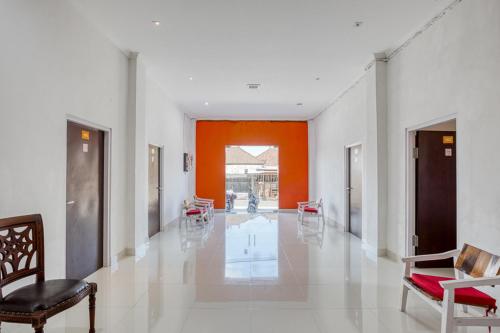 a hallway with orange and white walls and chairs at RedDoorz near Bali Zoo Ubud in Sukawati