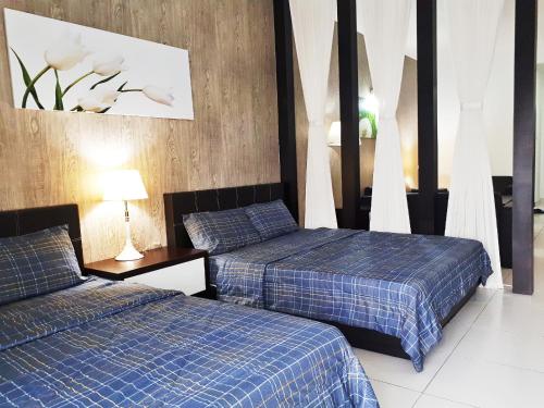 新山的住宿－巴余海濱度假村（一室公寓民宿），配有蓝色拼盘床单的客房内的两张床