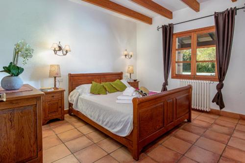 una camera con letto in legno e finestra di Villa Les Figueres By homevillas360 a Pollença