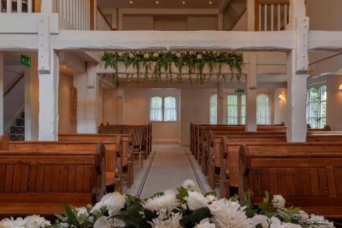 an aisle in a church with wooden pews and flowers at Orsett Hall in Orsett