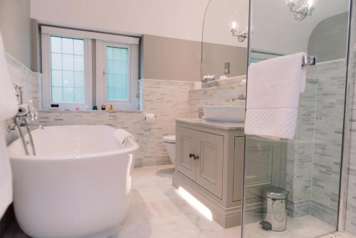 a white bathroom with a tub and a sink at Lucknam Park Hotel in Chippenham