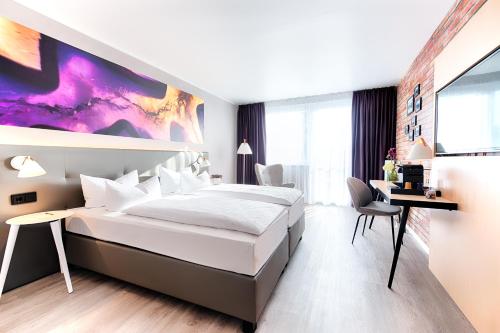 a bedroom with a large white bed and a desk at ACHAT Hotel Offenbach Plaza in Offenbach