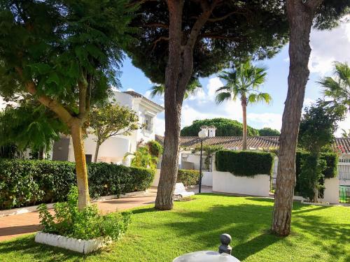 a yard with palm trees and a white house at Apartamento Zinna in Chiclana de la Frontera
