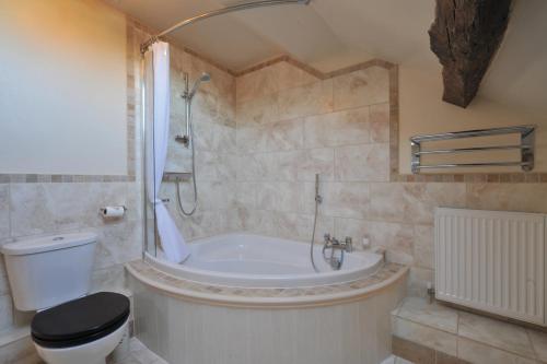 a bathroom with a tub and a toilet and a shower at Priory hotel in Cartmel
