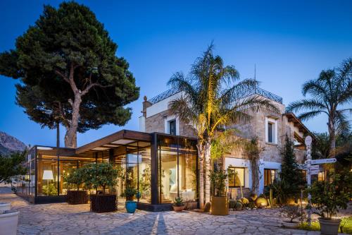 une maison avec beaucoup de fenêtres et de palmiers dans l'établissement Magaggiari Hotel Resort, à Cinisi