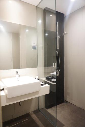 La salle de bains est pourvue d'un lavabo blanc et d'une douche. dans l'établissement ARTOTEL Thamrin Jakarta, à Jakarta