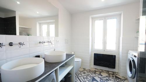 a white bathroom with two sinks and a toilet at Le Bastion in Menton