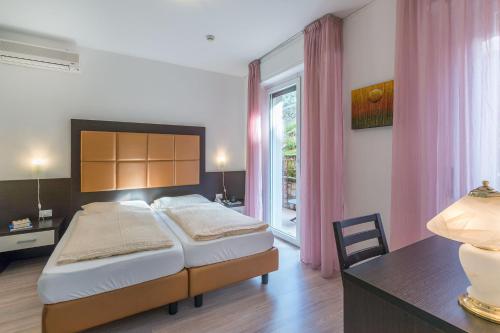 a bedroom with a bed and a desk and a window at Hotel Villa Carmen in Malcesine