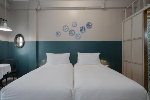 two beds in a room with blue and white plates on the wall at Blu Monkey Boutique Phuket Town in Phuket Town
