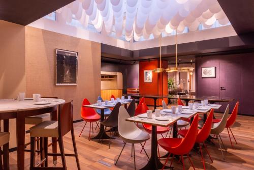 une salle à manger avec des tables et des chaises rouges dans l'établissement Golden Tulip Opera de Noailles, à Paris
