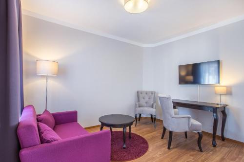 a living room with a purple couch and a table and chairs at Hotel Annaberg in Bad Dürkheim