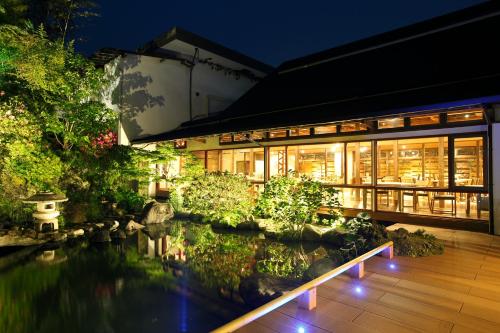 a building with a pond in front of it at Yumeguri no Yado Yoshiharu in Izunokuni