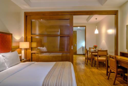 a bedroom with a bed and a desk and a table at Mansion Garden Hotel in Olongapo