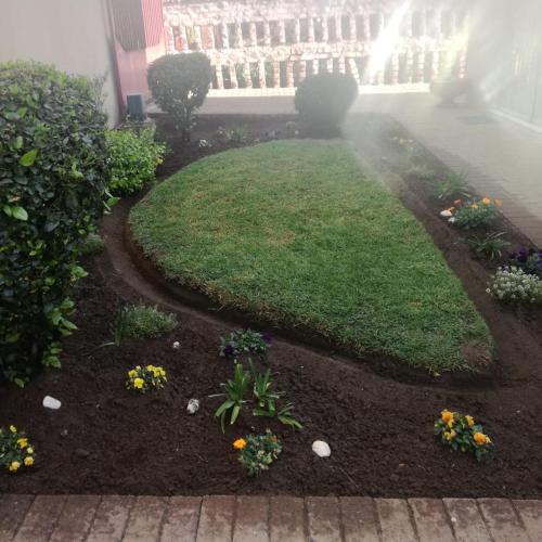 a yard with a lawn with flowers and a building at faces guesthouse in Bethlehem
