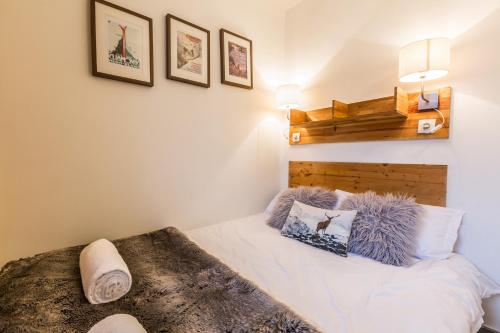 sypialnia z białym łóżkiem z drewnianym zagłówkiem w obiekcie Apartment Batiment F w Chamonix-Mont-Blanc