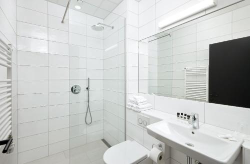 a white bathroom with a toilet and a sink at Hotel Cabin in Reykjavík