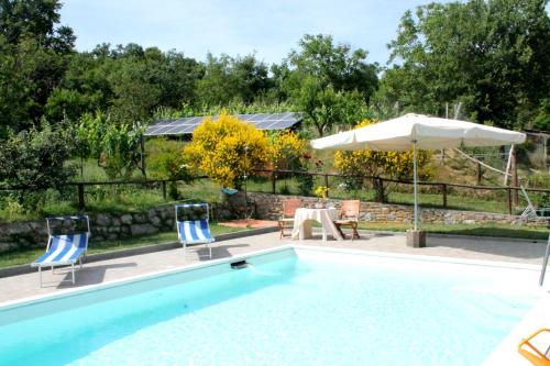 una piscina con tavolo, sedie e ombrellone di Casa Caldesi a Castiglion Fiorentino