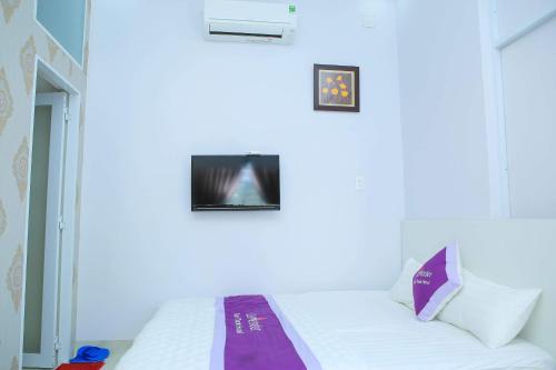 a bedroom with a white bed with two pictures on the wall at Lavender Tan Thanh Hotel mini resort in Cong Thanh (3)