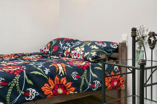a bed with a blue blanket with flowers on it at Smėlio Apartamentai in Anykščiai