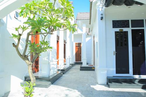 a white building with a tree in a courtyard at Lavender Tan Thanh Hotel mini resort in Cong Thanh (3)