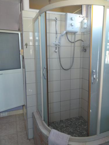 a shower with a glass door in a bathroom at Tyvabro Guesthouse in Mahébourg