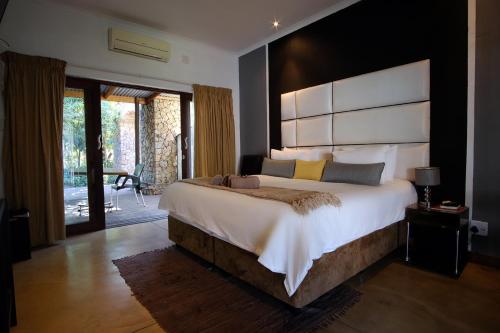 1 dormitorio con 1 cama grande y cabecero grande en Cu Guest House en Phalaborwa
