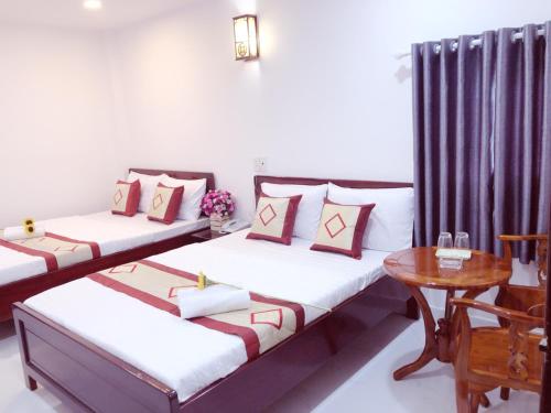 two beds in a room with a table and a table at Aurora Hotel in Ho Chi Minh City