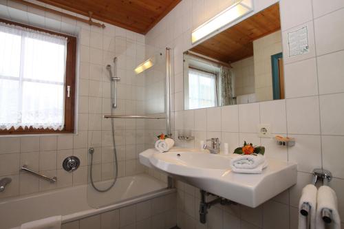 a bathroom with a sink and a shower and a tub at Hotel Sonne in Sankt Johann in Tirol