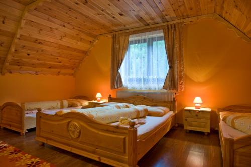 a bedroom with three beds and a window at PENZIONHARMONIA eu in Lendak