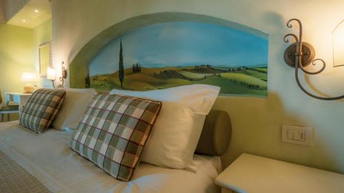 a bedroom with a bed with a painting on the wall at Hotel Borgo Di Cortefreda - Place of Charme in Tavarnelle in Val di Pesa