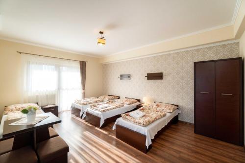 ザコパネにあるDW Harendaのベッド3台とテーブルが備わるホテルルームです。