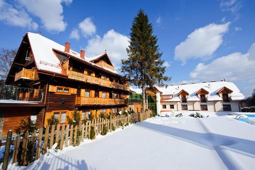 a wooden building in the snow with a fence at Hotel Modrzewiówka in Lanckorona