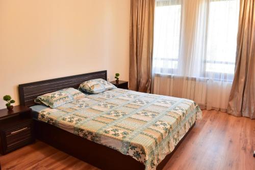 a bedroom with a bed with a floral bedspread and a window at Cedar Lodge in Bansko