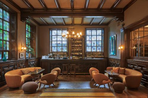 eine Bar mit Stühlen und Tischen in einem Zimmer mit Fenstern in der Unterkunft Grand Hotel Terminus in Bergen