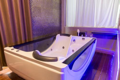 a white bath tub in a bathroom with a window at ลอฟท์แอทสีมา สาขา2 in Nakhon Ratchasima