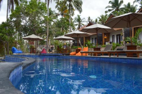 een zwembad met stoelen en parasols naast een resort bij Meket Bungalows in Nusa Penida
