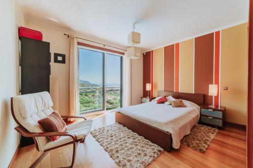 a bedroom with a bed and a chair and a large window at Villa Sol in Ponta do Sol