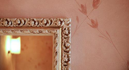an ornate mirror in a room with a wall at Hotel Borgo Di Cortefreda - Place of Charme in Tavarnelle in Val di Pesa