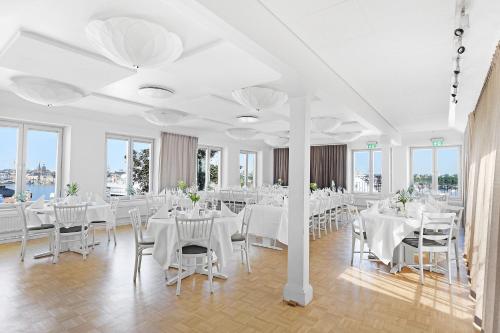 a room with white tables and chairs and windows at Ersta Hotell & Konferens in Stockholm