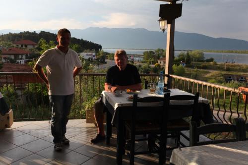two men sitting at a table on a balcony at Guesthouse To Fragma in Lithótopos