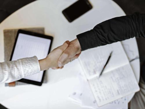 two people shaking hands at a table with a laptop at ibis Styles Hotel Gelsenkirchen in Gelsenkirchen