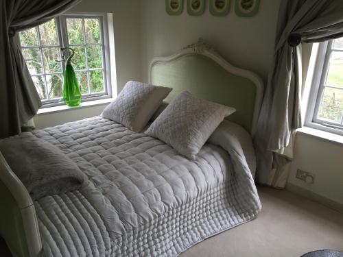 a white bed in a bedroom with two windows at Castle Mill Bed and Breakfast in Dorking