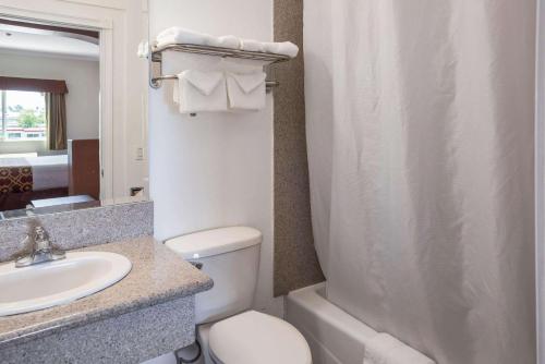 a bathroom with a white toilet and a sink at Rodeway Inn & Suites Pasadena in Pasadena
