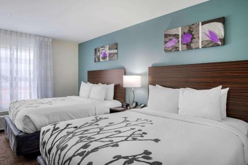 a hotel room with two beds and a window at Sleep Inn & Suites near Westchase in Houston